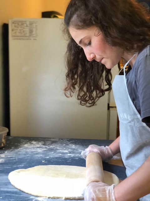 girl rolling out dough for pizza