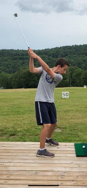 boy swinging golf club at driving range