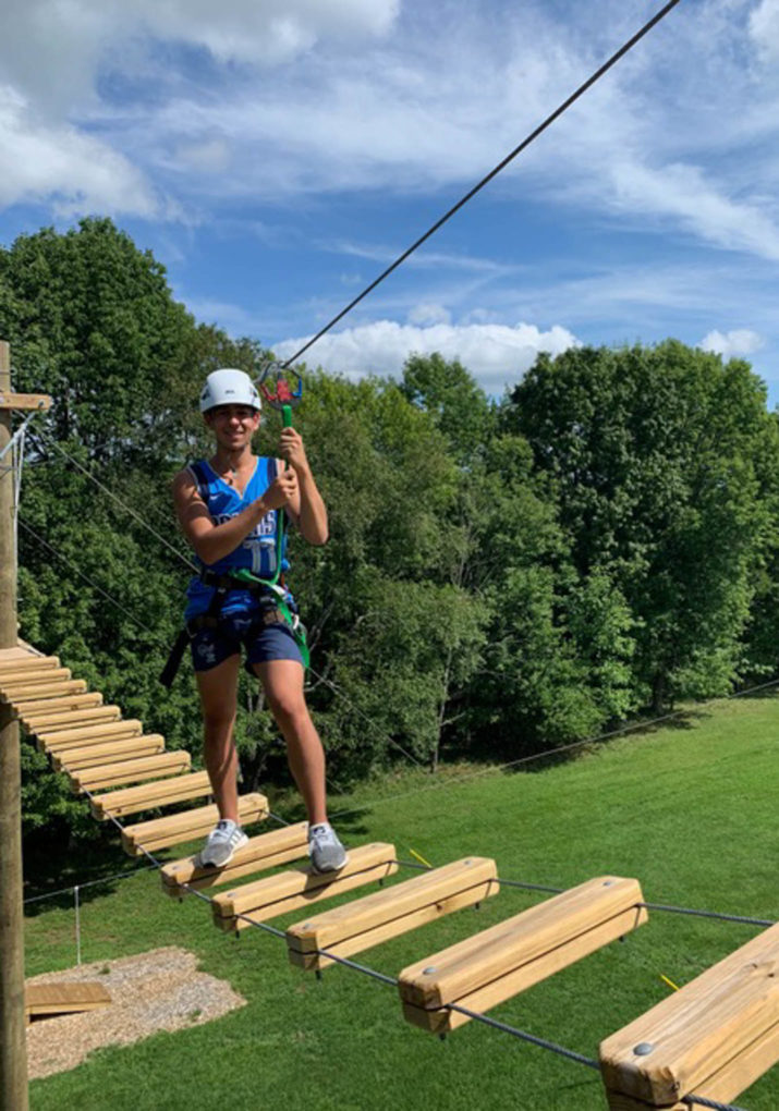 Camper walking across a bridge on the challenge course