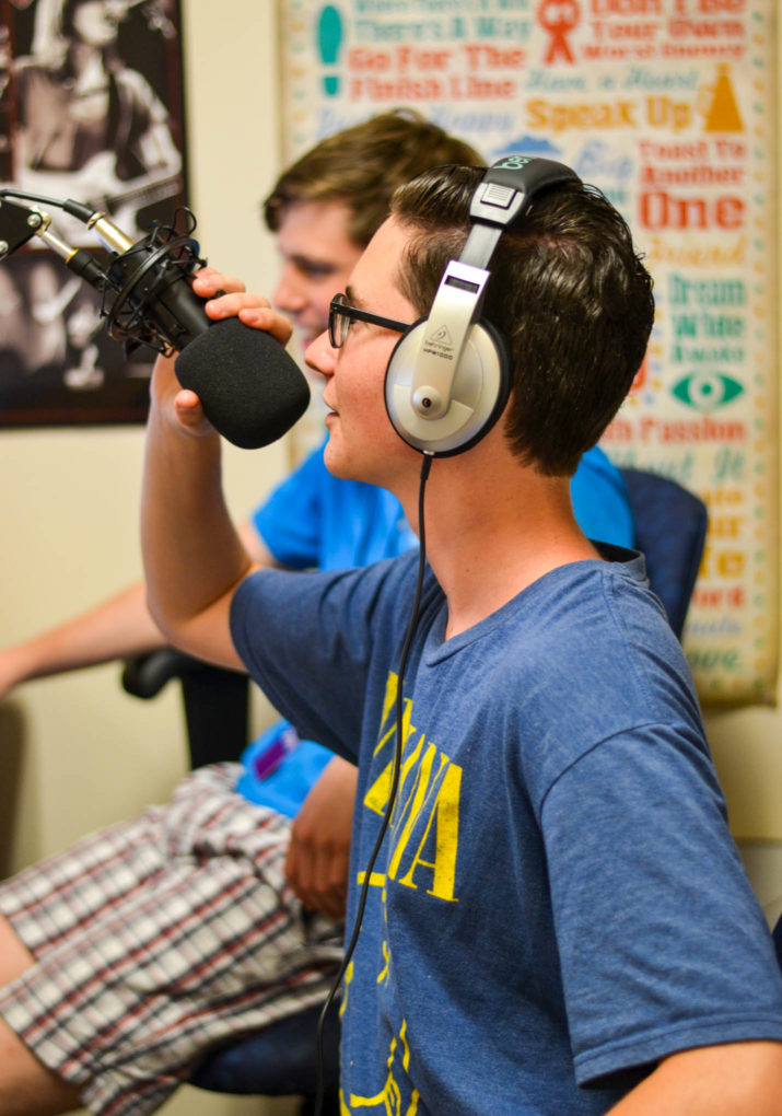 Camper speaking into a microphone in a radio studio