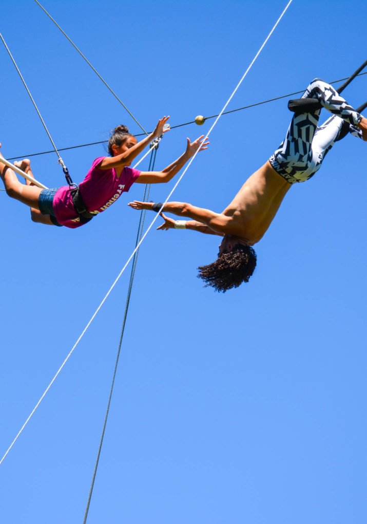 Instructor catching camper doing a trapeze stunt