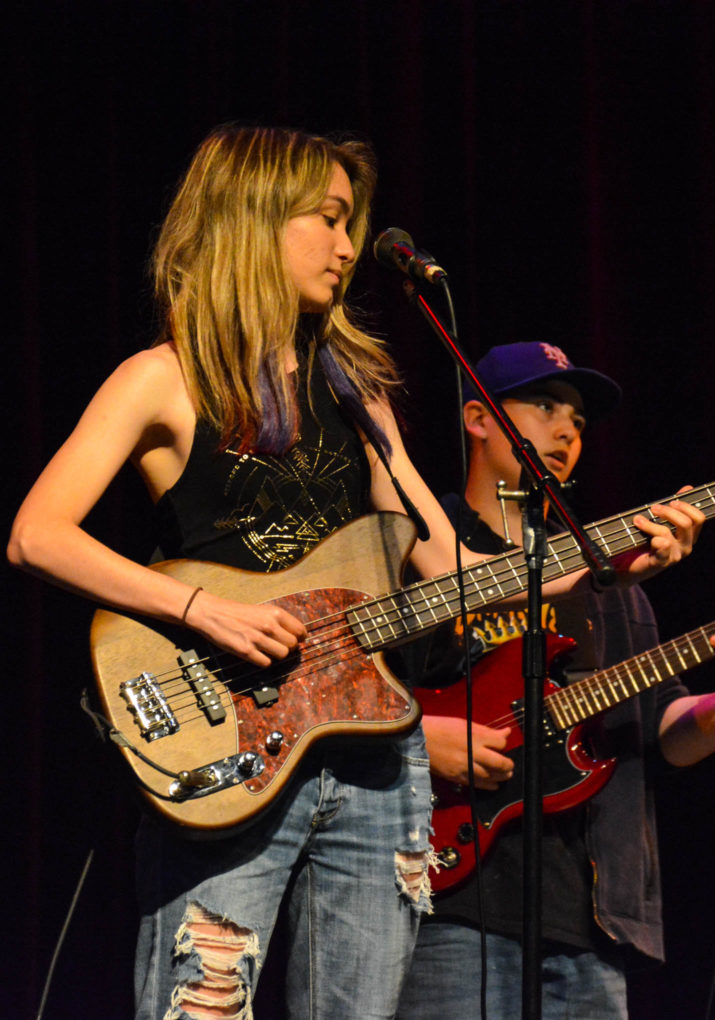 Girl camper playing the guitar on stage in a band