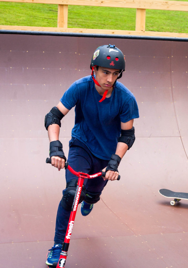 Camper riding the half pipe on a scooter