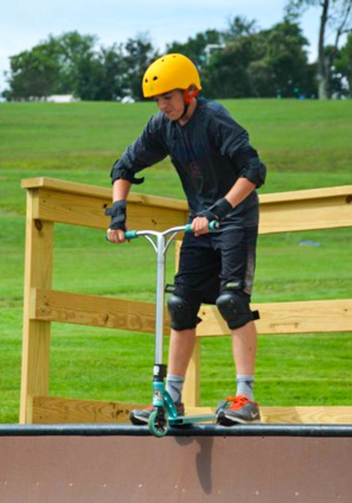 Camper about to skateboard down a half pipe ramp