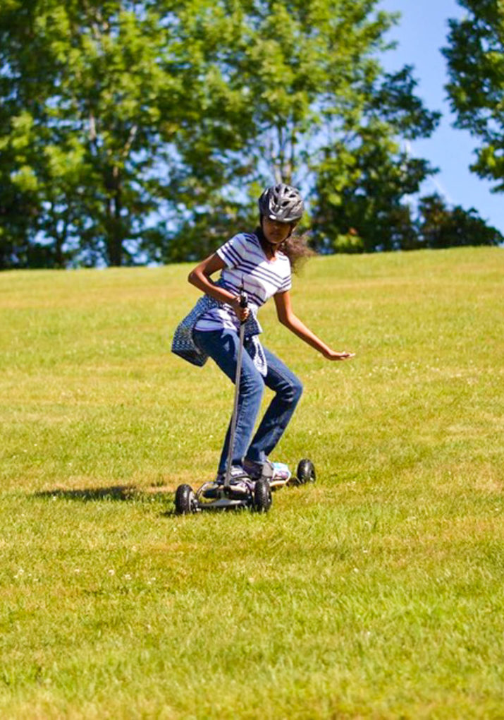 Camper boarding down a grassy hill