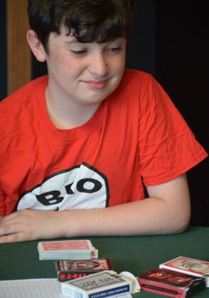 Boy sitting at a table with a deck of cards