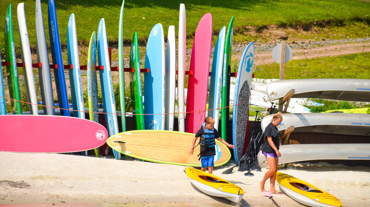 Campers on the lake shore getting ready to paddle board