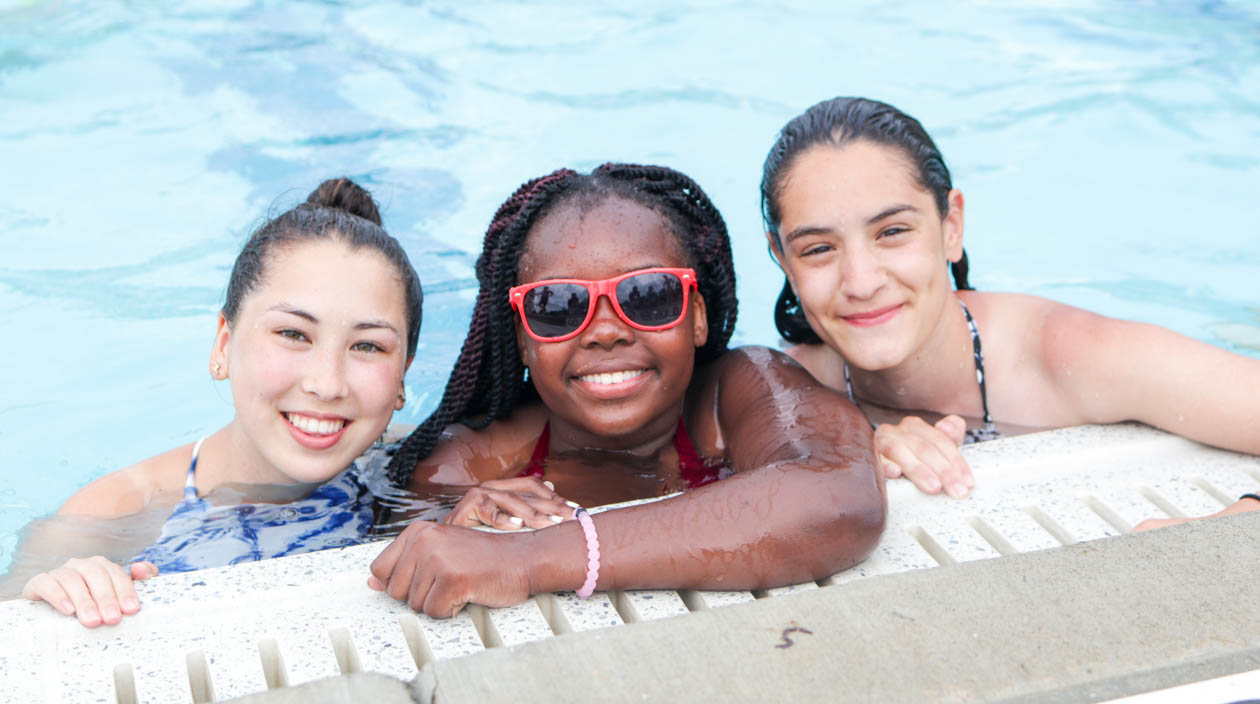 Three girl campers smiling in the pool