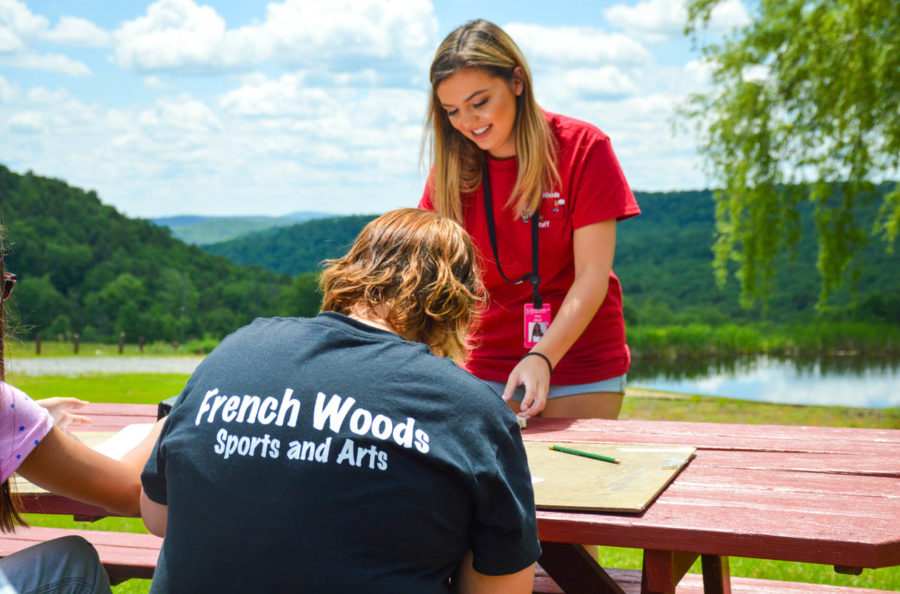 Staff member helping out with art campers