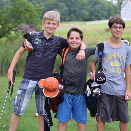 kids playing golf smiling at camera.