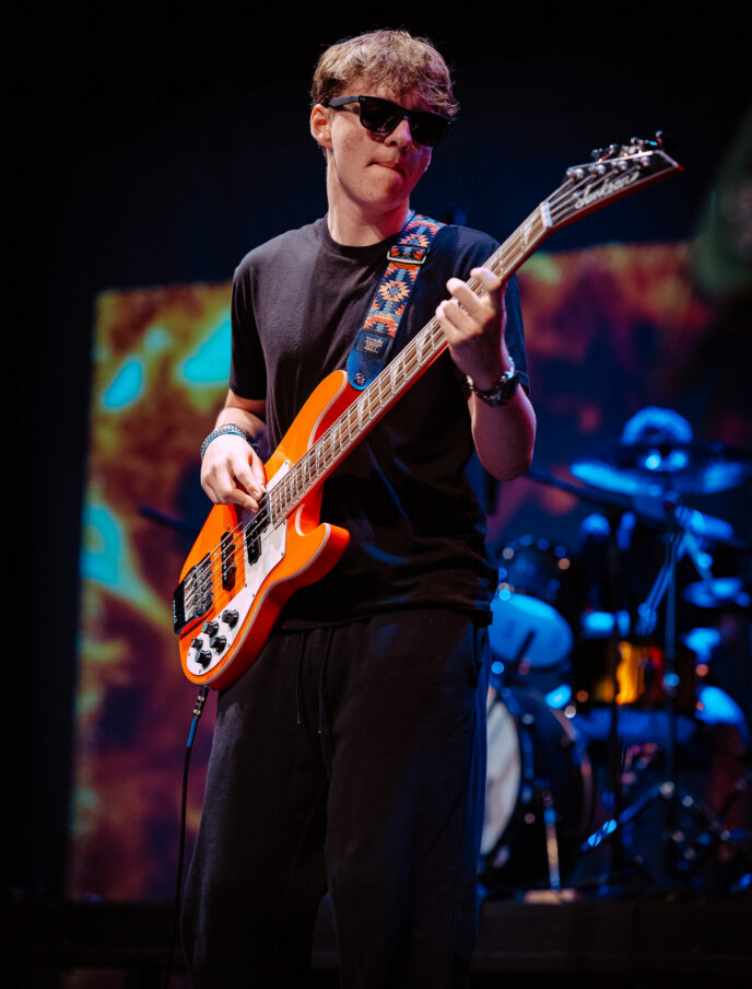 A teen boy playing the electric guitar on stage at summer camp