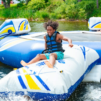 Teen boy jumping onto an air pillow in the French Woods summer camp lake