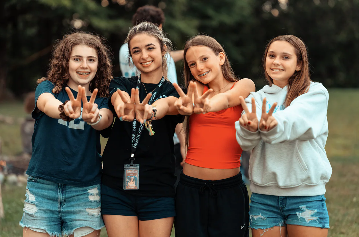 Four teen campers posing together during a campfire gathering at New York Teen Camp